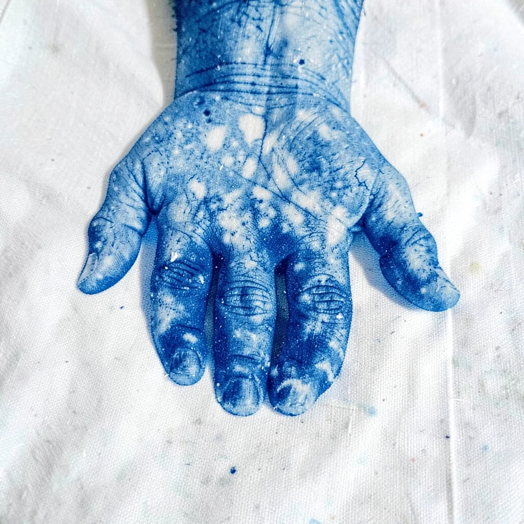 A back of the hand pressed down — knuckle detail and vein lines in Prussian blue