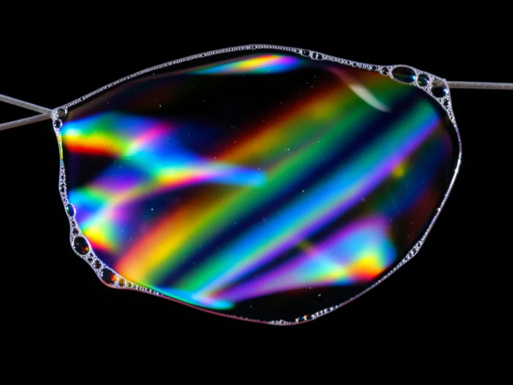 Soap film viewed in reflected light only, dark background with vivid interferenc