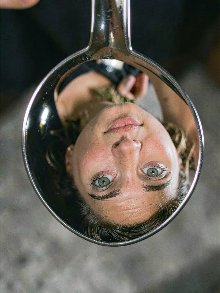 A face reflected in a spoon, features stretched and inverted