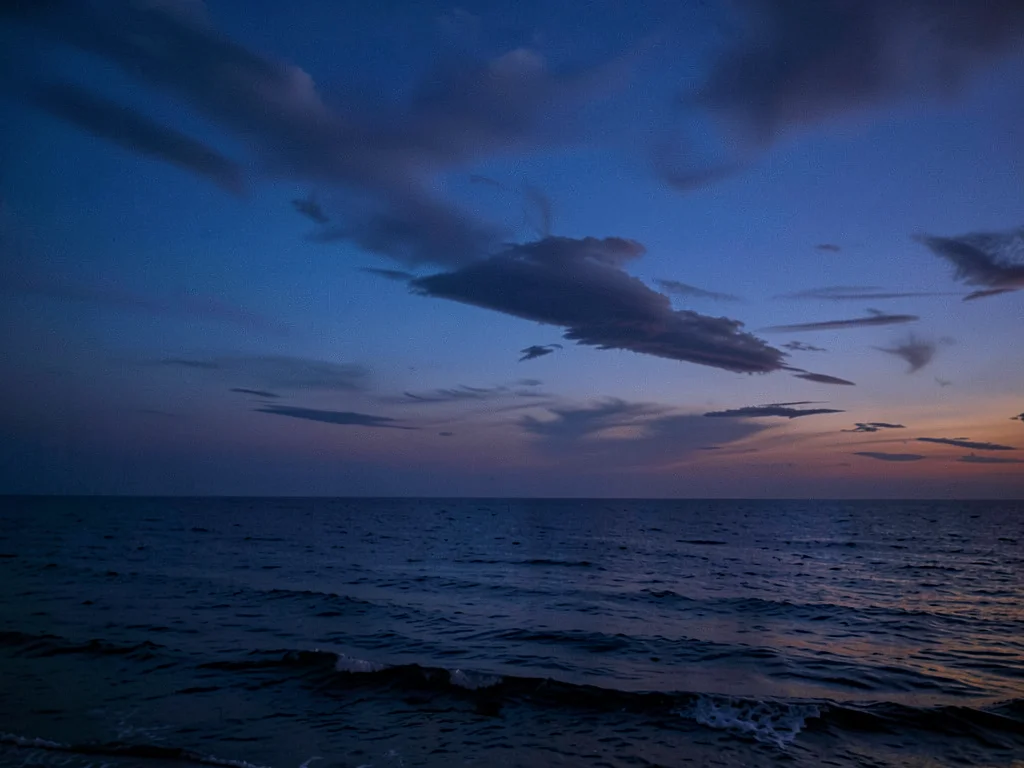 Sunset to blue hour compressed into single gradient sky over ocean