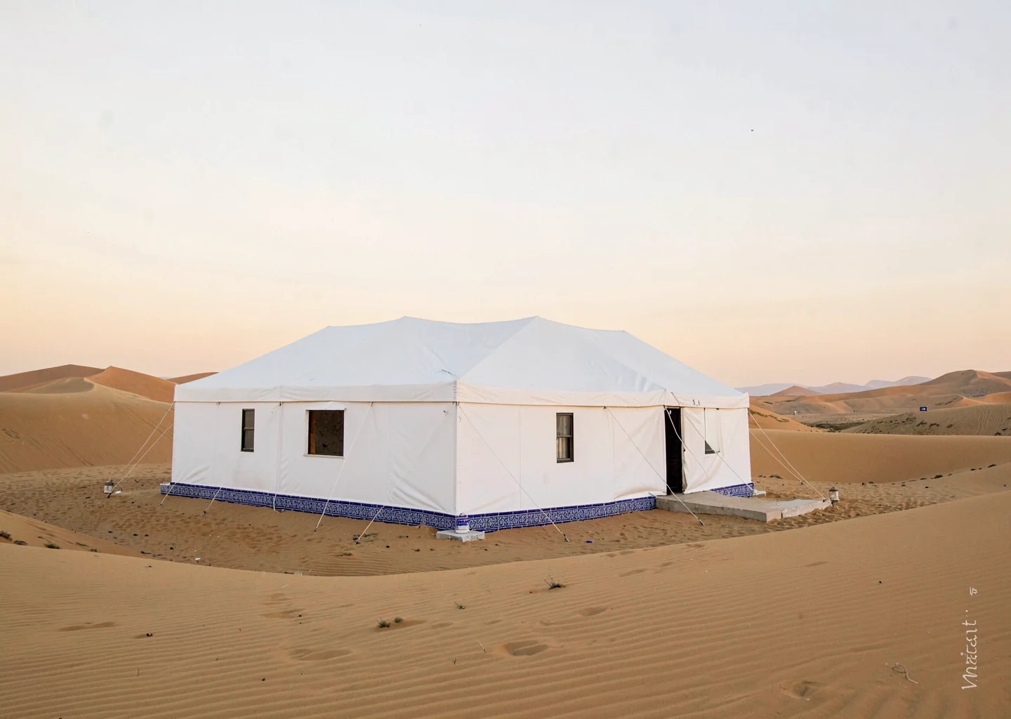 Extreme minimalist restraint of Muscat, Oman, white tent camp in golden sand dun