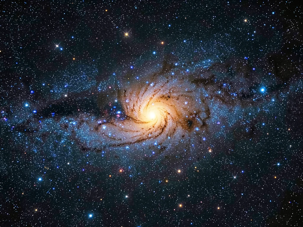A face-on spiral galaxy with blue-white young star clusters in the arms and a wa