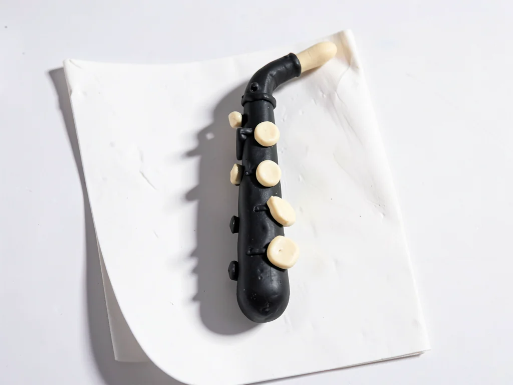 Stubby clay clarinet in deep black with chunky cream-toned keys and stubby reed 