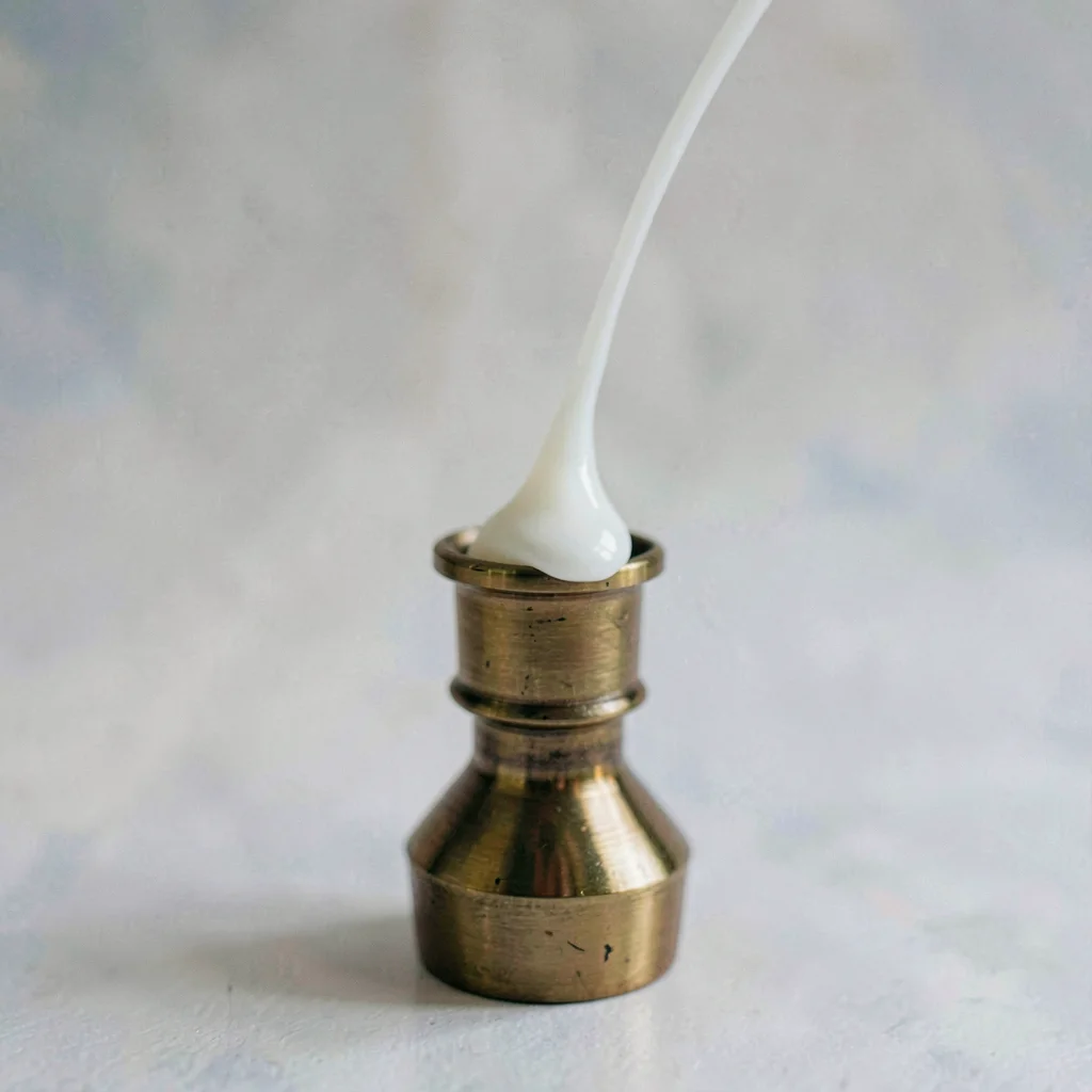 Mineral-cut macro of a candle wax drip down a brass holder, hard top light