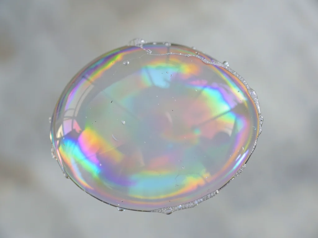 Soap bubble wall thinning before pop, iridescent membrane, impermanence magnifie