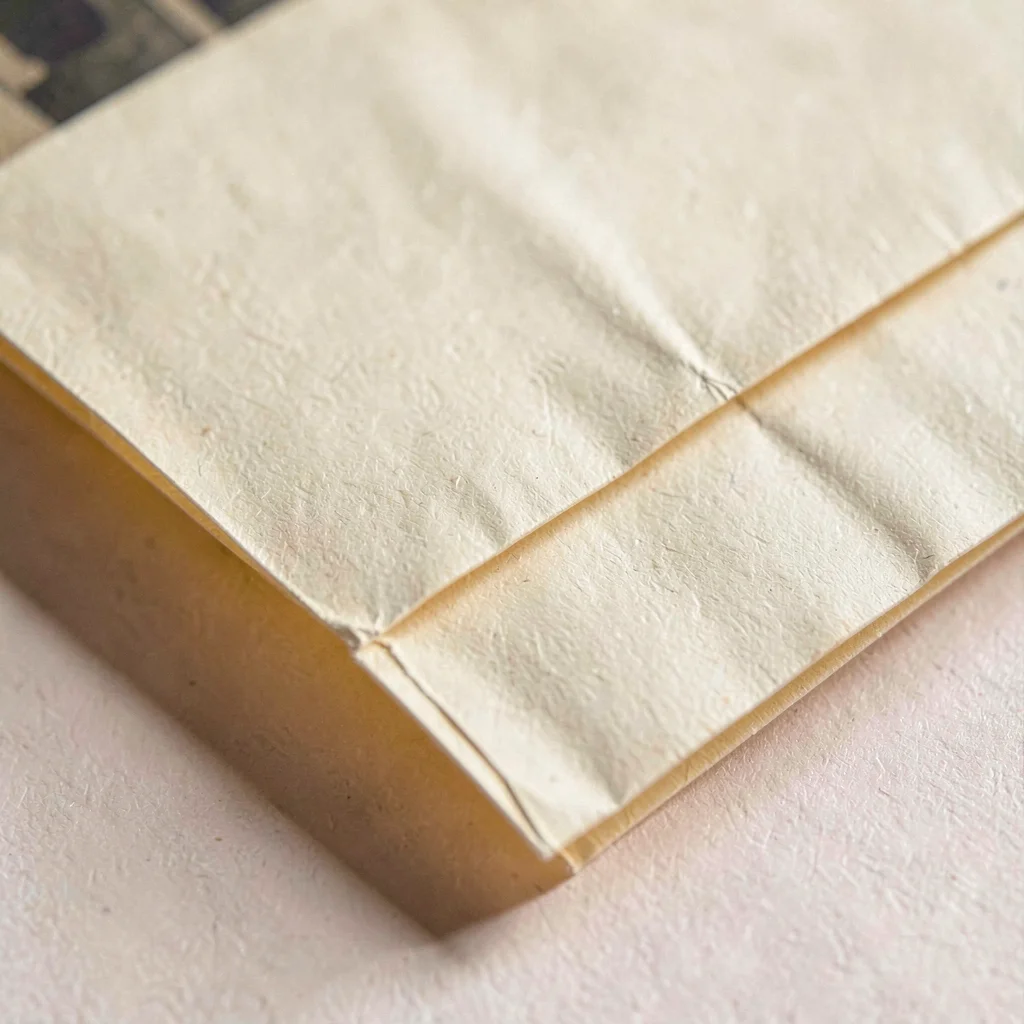 Macro of a folded film inventory sleeve with crease shadows and warm cream paper