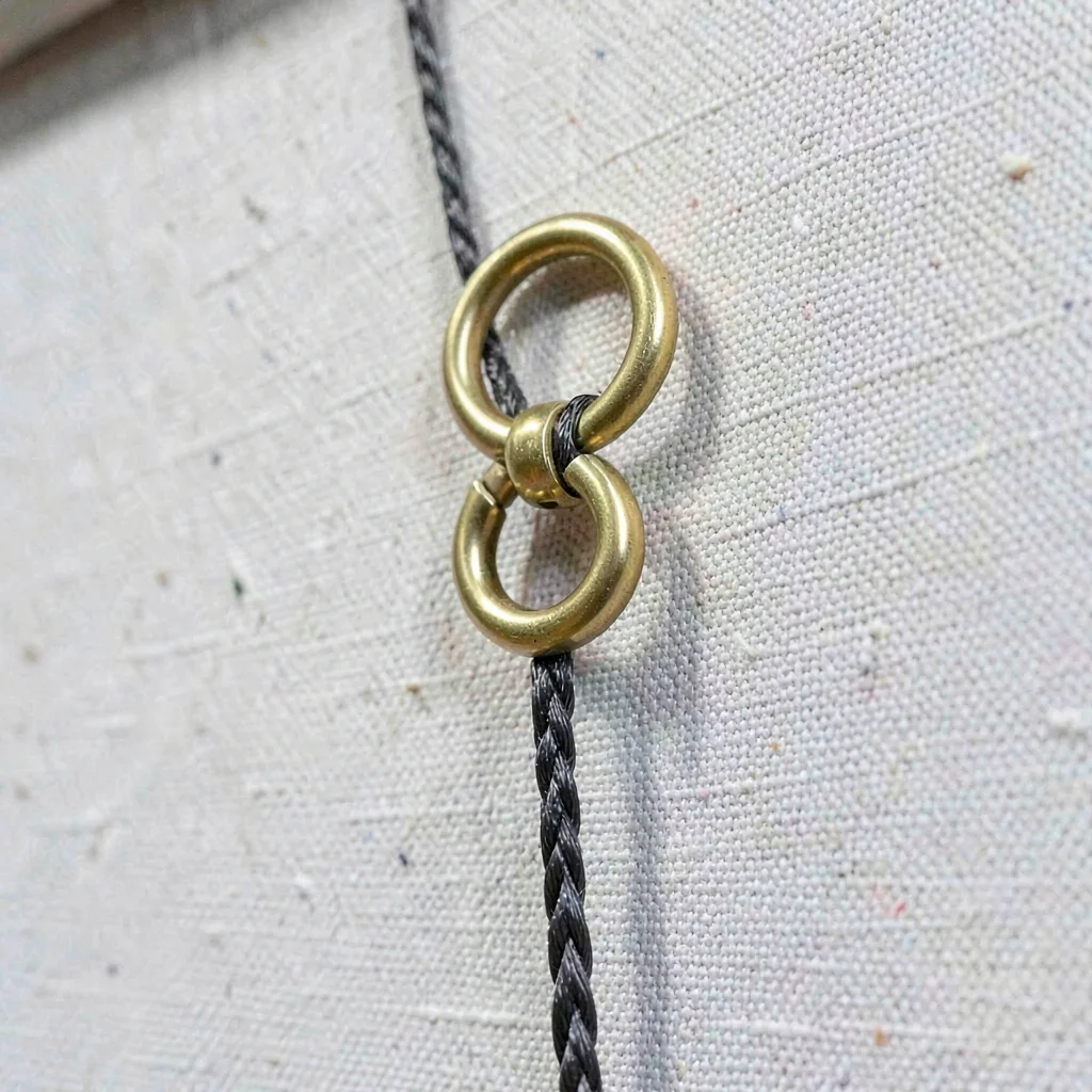 Macro of a hanging hardware on the back of a canvas, brass d-ring and braided wi