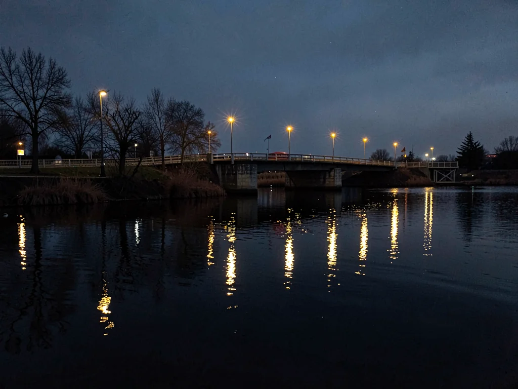 Bridge lights reflected in darkening water