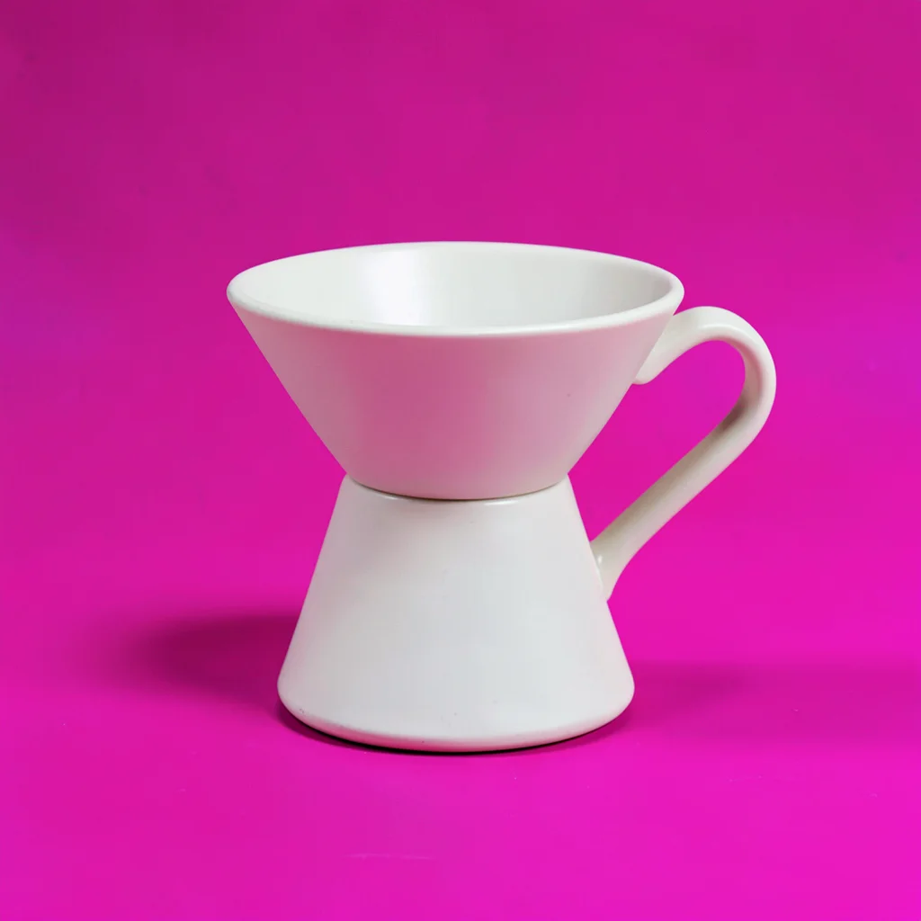 ceramic pour-over coffee dripper in matte cream centred on a saturated fuchsia b