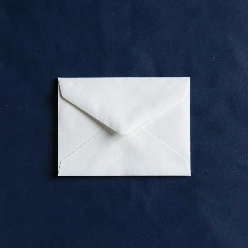 Centered hero of a small white envelope on a deep navy backdrop, even diffuse li