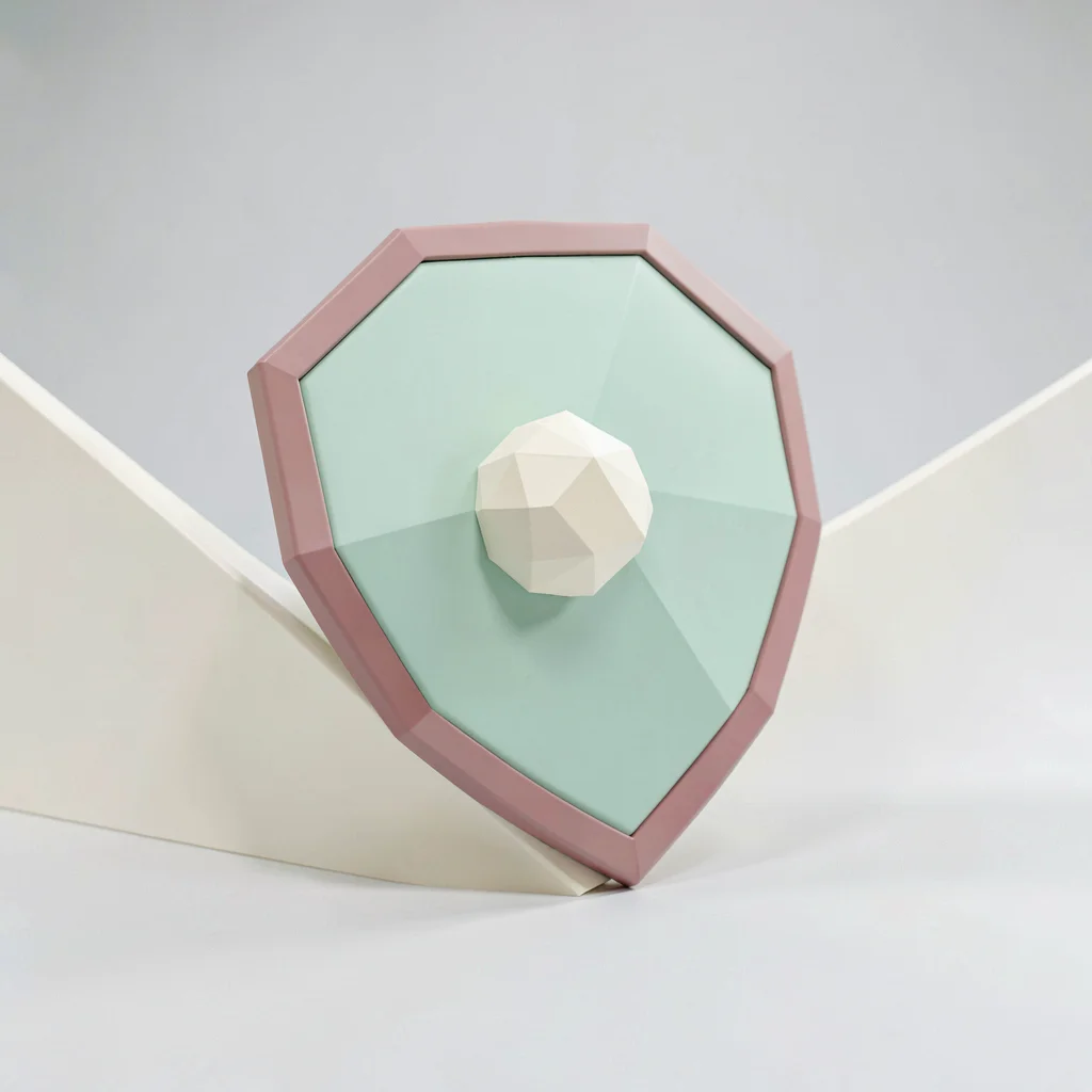 Round-faced mint-green lowpoly shield with a chunky cream boss and faceted dusty