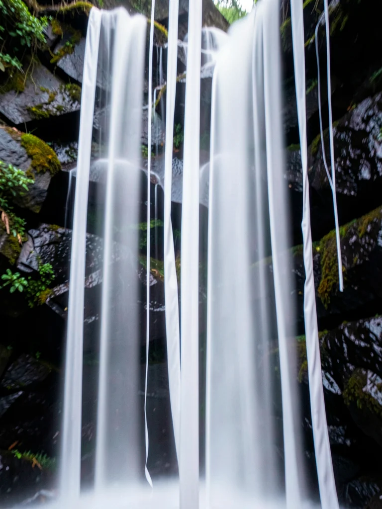 Waterfall reduced to vertical white silk ribbons against dark rock