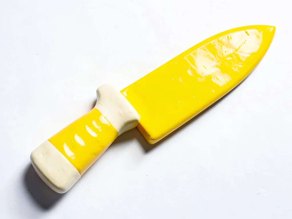 Knife-shaped chunky clay chef knife in primary yellow with stubby cream-toned bl
