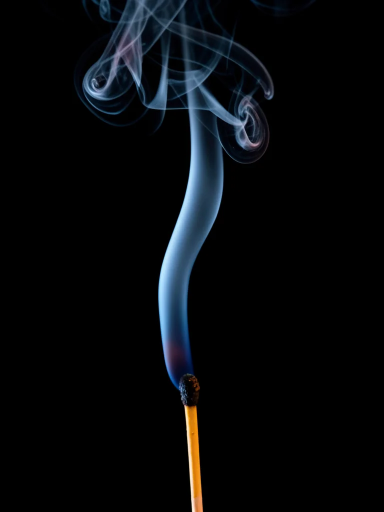 A match just extinguished, the smoke trail rising from the glowing ember, sulfur