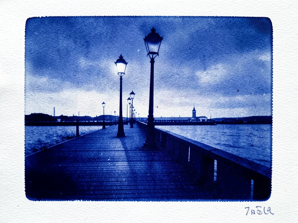 A row of street lamps along a waterfront boardwalk at dusk