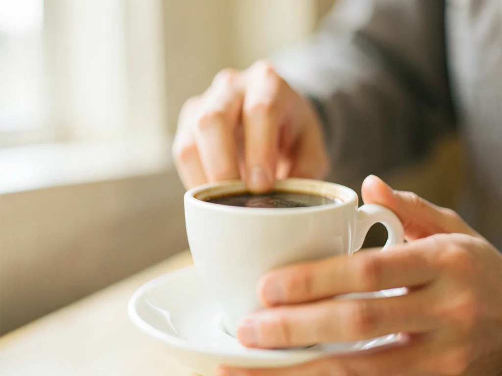 Hand reaching for coffee cup, background dissolved
