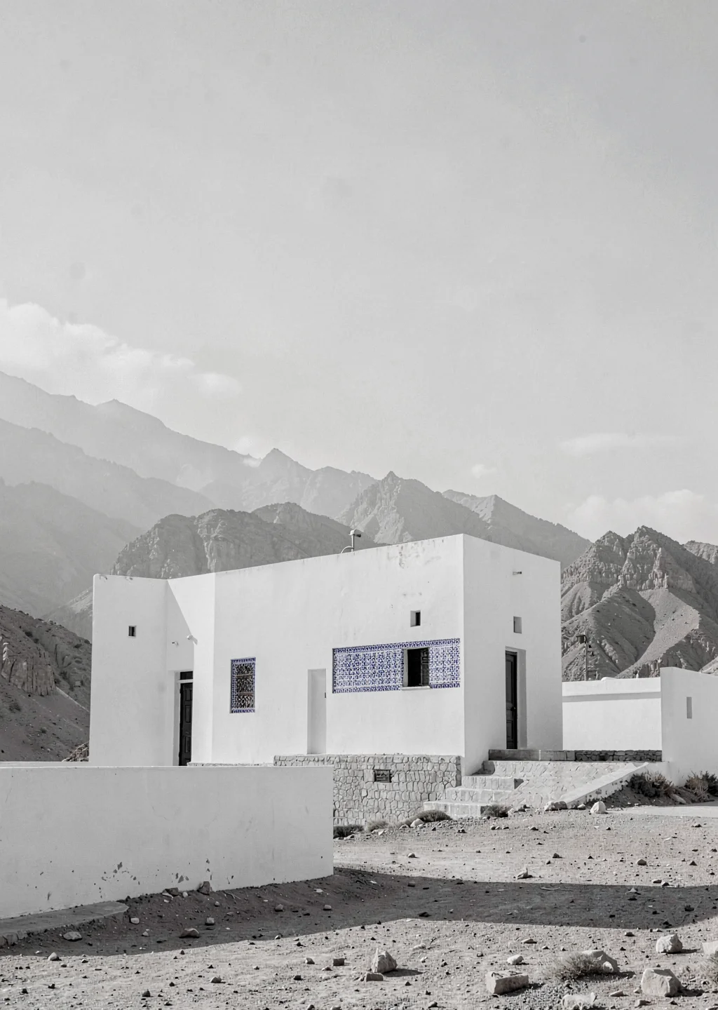 Extreme minimalist restraint of Muscat, Oman, fort tower against mountains, mono