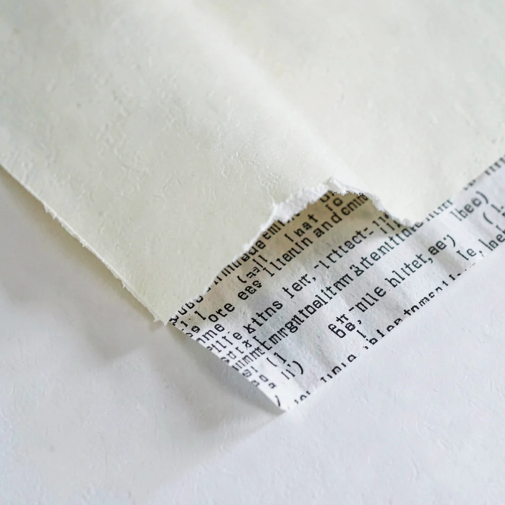 Inside spread of a torn paper edge revealing a printed fragment of code-like pat