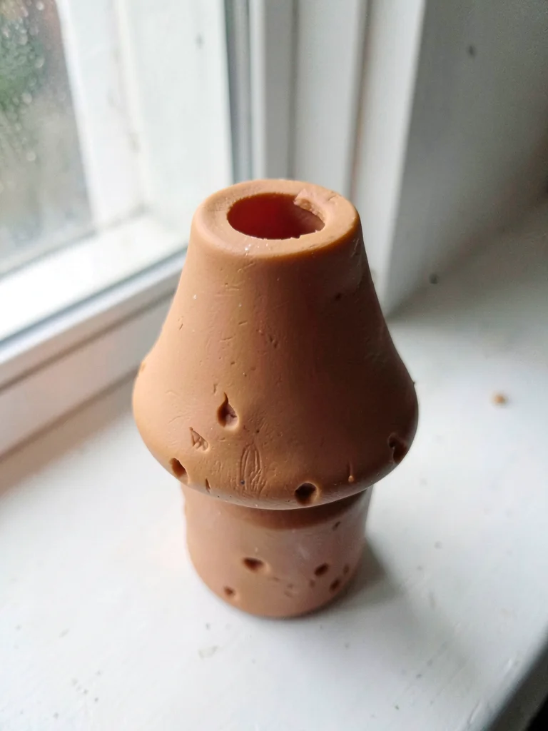 Lit-from-above ochre lamp shape with a slumped shade and fingernail dents along 