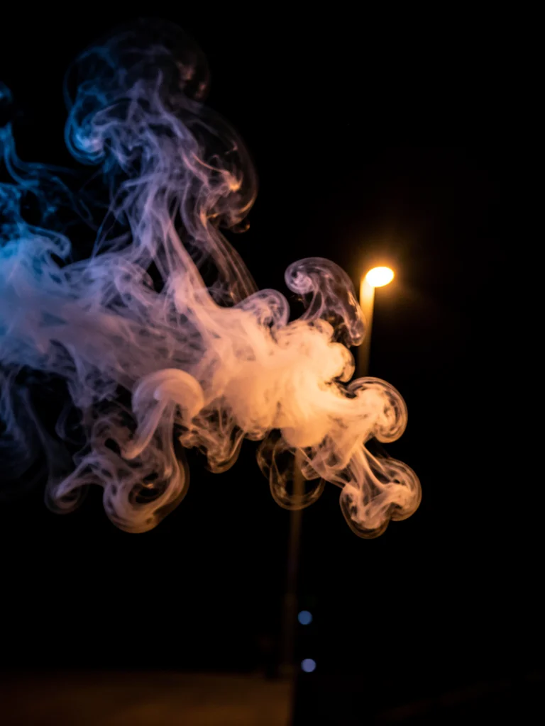 Breath in cold air, backlit by a streetlight, the warm vapor dispersing into the