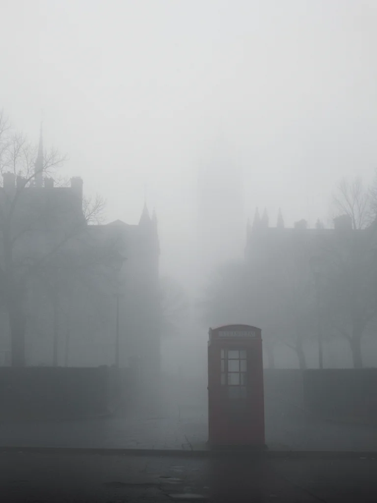 A foggy London morning: a red telephone booth as the only color anchor, everythi