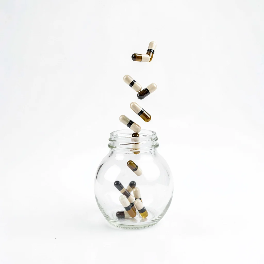 Minimal composition of capsules tumbling from a tilted bottle on white seamless