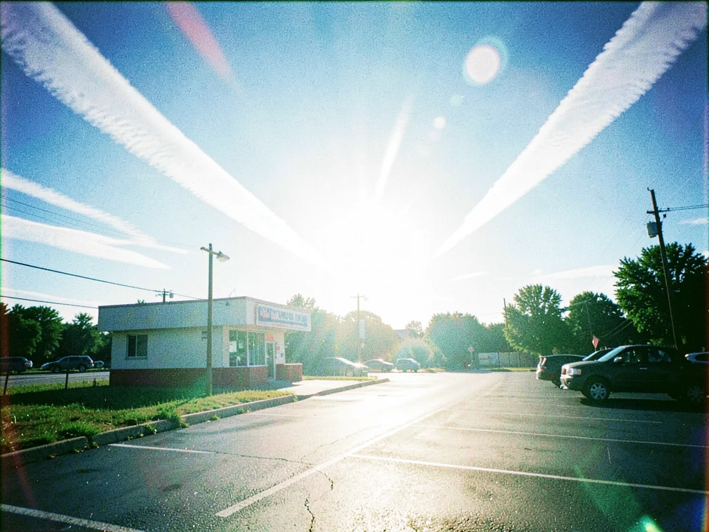Asphalt parking lot of a closed roadside diner shimmering in midday heat with tw