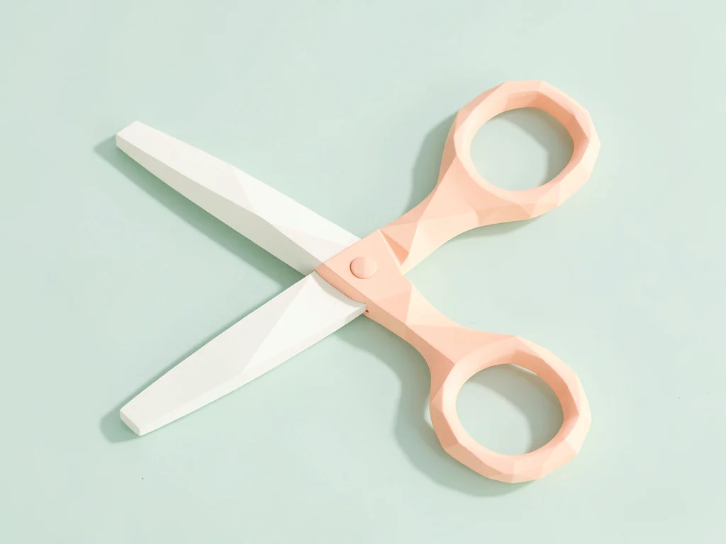 Crisp cream lowpoly scissors with peach loop handles and triangulated blades, so