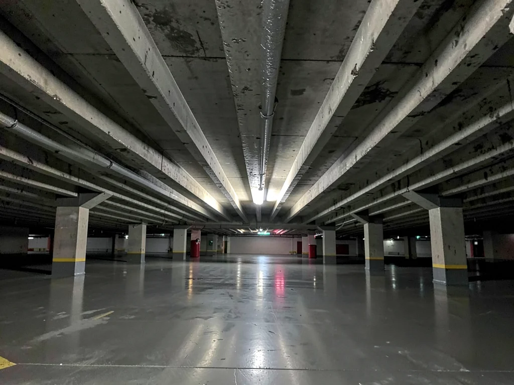Underside of a parking deck repeating ribbed concrete beams in perfect rhythm, s