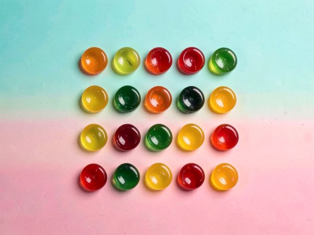 Eighteen gummy candies knolled in a precise six-by-three grid sorted by color ac