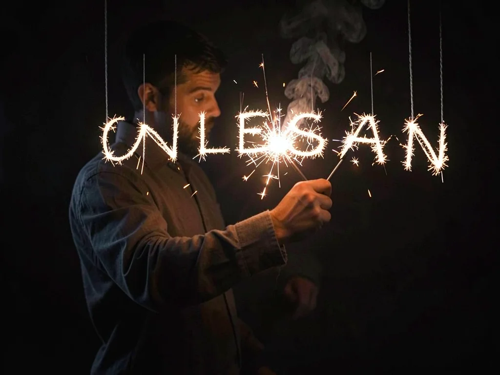 A person writing a word with a sparkler during a 5-second exposure, the letters 