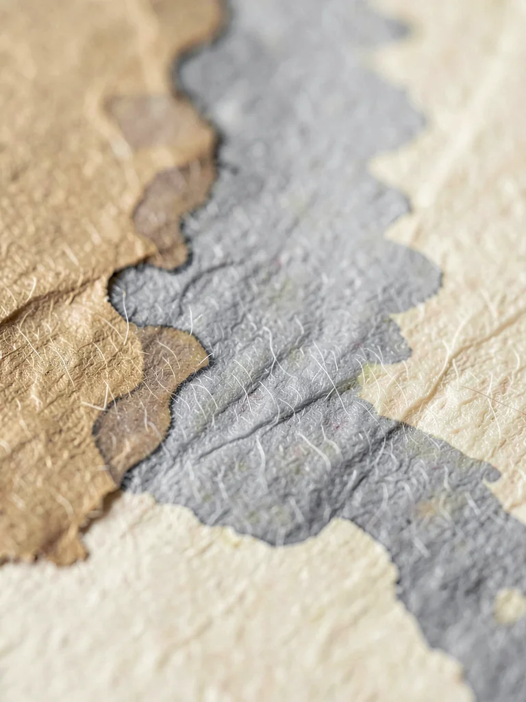 Abstract ink bloom diffusing across deckle cotton as soft grey cloud bleeding in