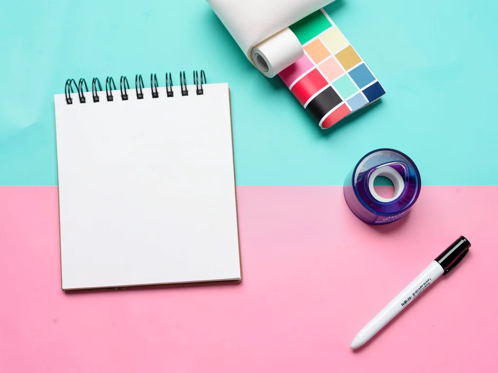 Studio knolling of designer tools a sketchpad a roll of color swatches a chunky 