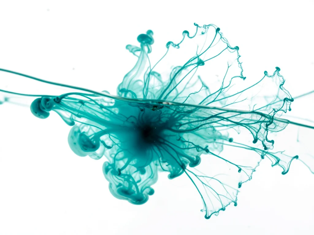 Turquoise ink spreading on wet paper like ocean wave cresting, macro
