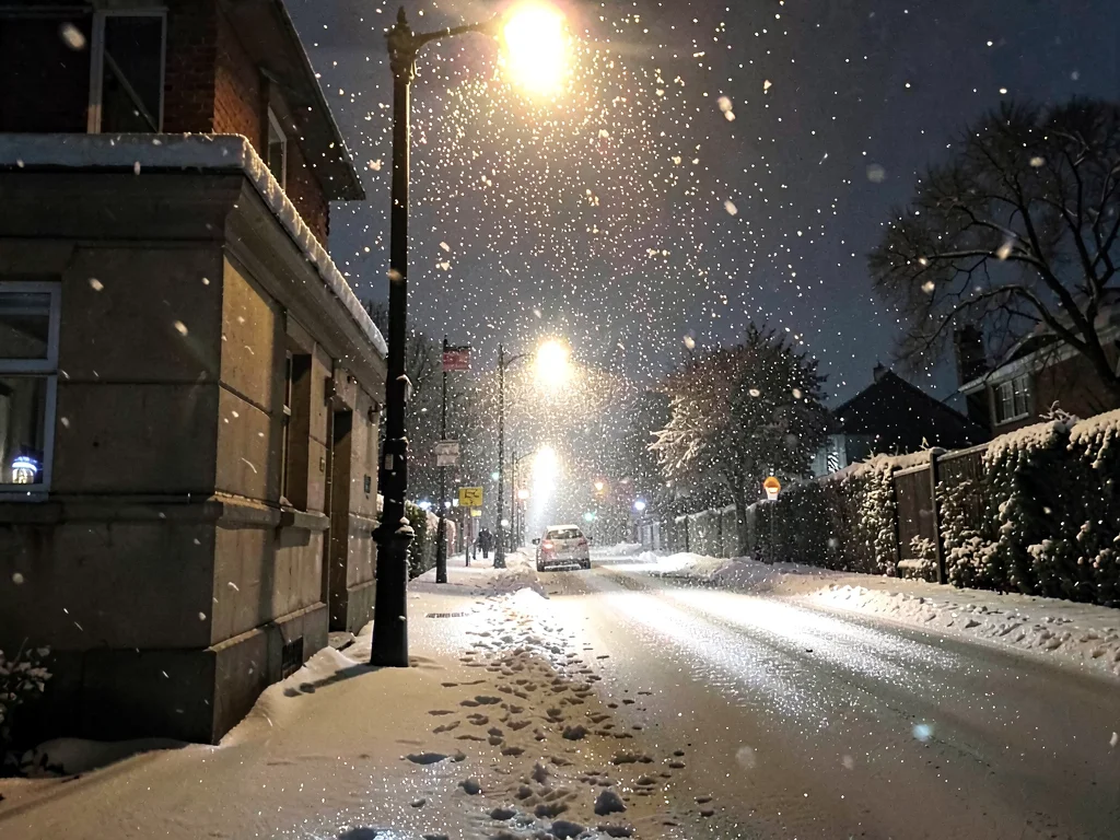 Snow falling backlit by streetlight