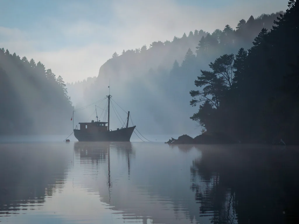 Fishing boat becoming silhouette in mist