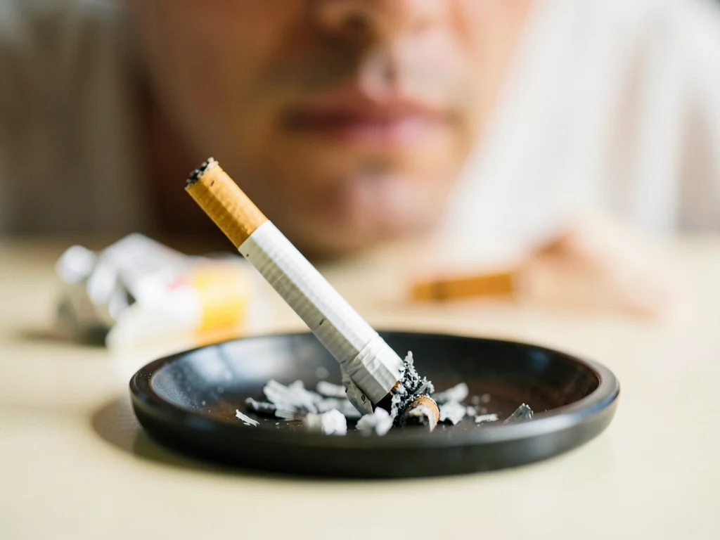Cigarette being crushed in ashtray, filter sharp and precise, crumpled pack soft