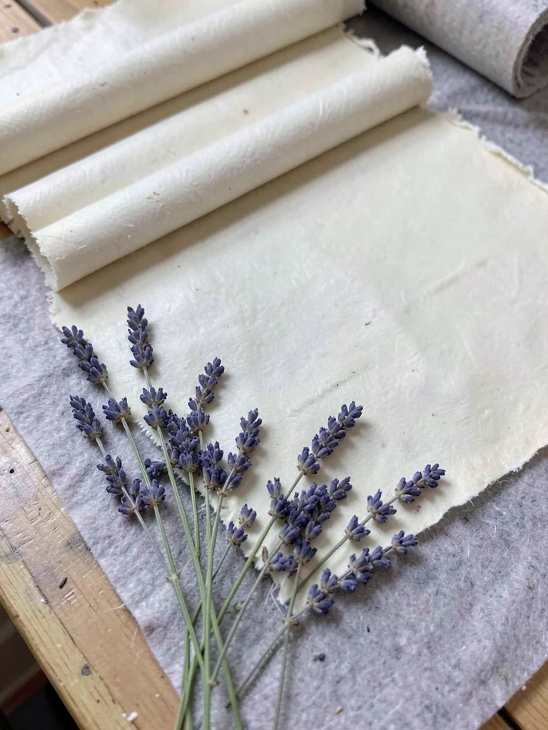 A handmade paper sheet with lavender sprigs embedded along the bottom margin