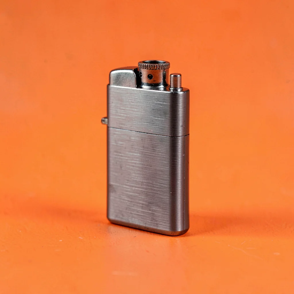 small refillable lighter in brushed gunmetal at three-quarter angle on a saturat
