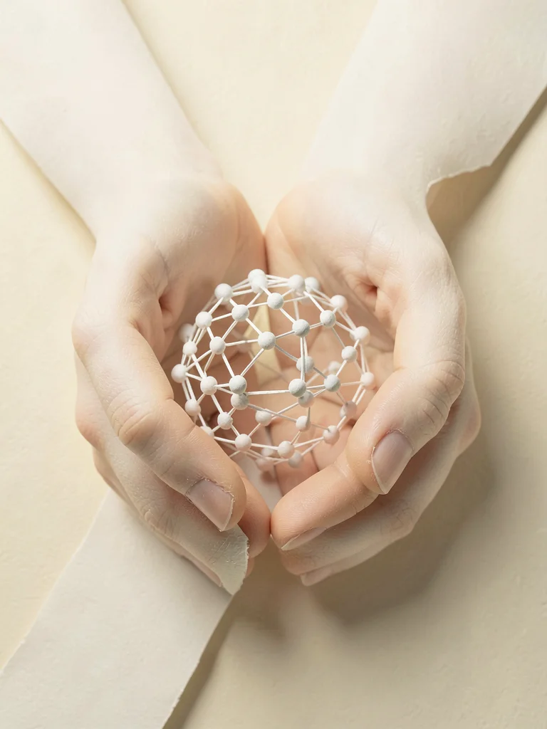 Two oversized cupped hands cradling a small globe woven from connected paper dot