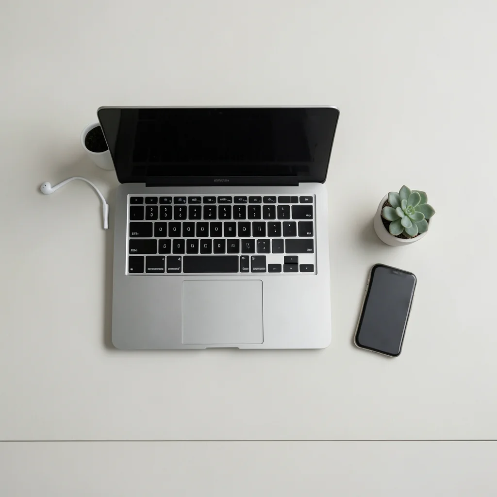 Overhead shot of a tidy desk with laptop, smartphone, earbuds, and a small succu