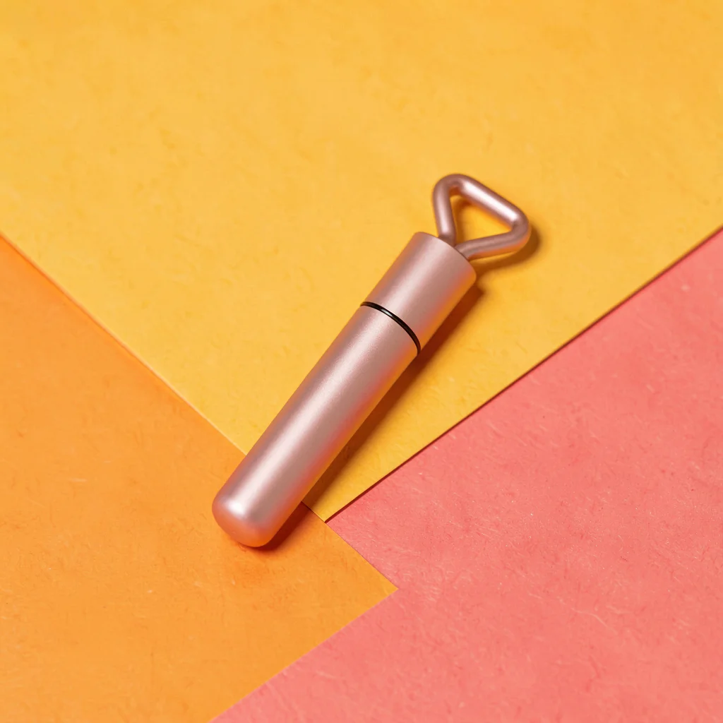 single matte-rose-gold mini-derma-roller pen at slight tilt on a saturated marig