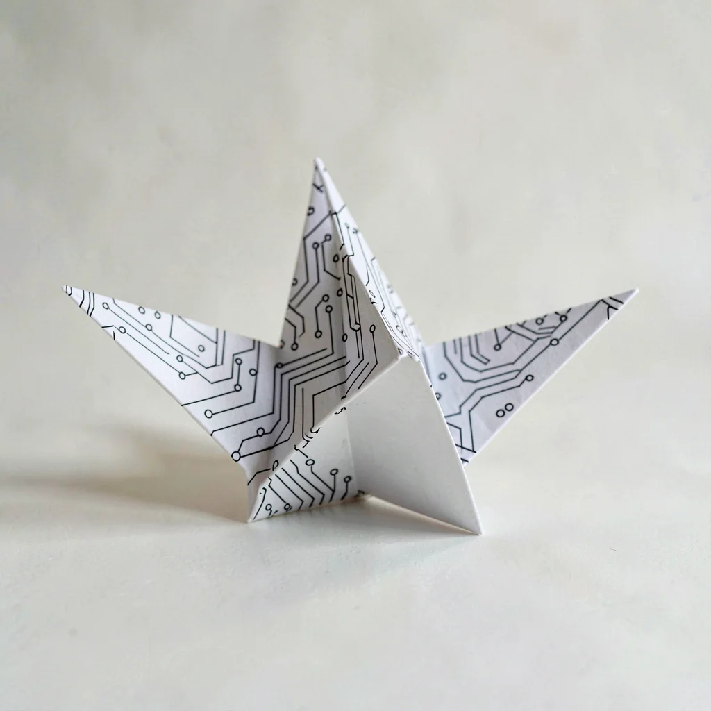 Cover plate of a folded paper crane mid-unfurl revealing a circuit pattern print
