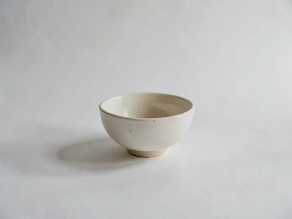 One ivory ceramic bowl placed off-center on an empty white-grey expanse, soft wi