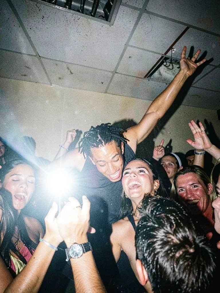 Crowd surfer caught from below, flash freezing sweat droplets and reaching hands