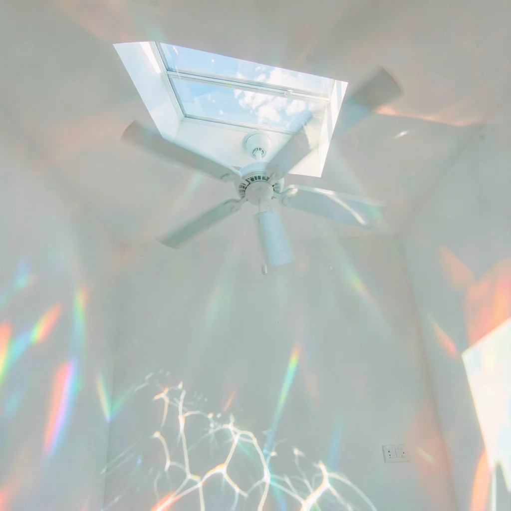 Soft diffused tropical light filtering through water vapor, A ceiling fan rotati