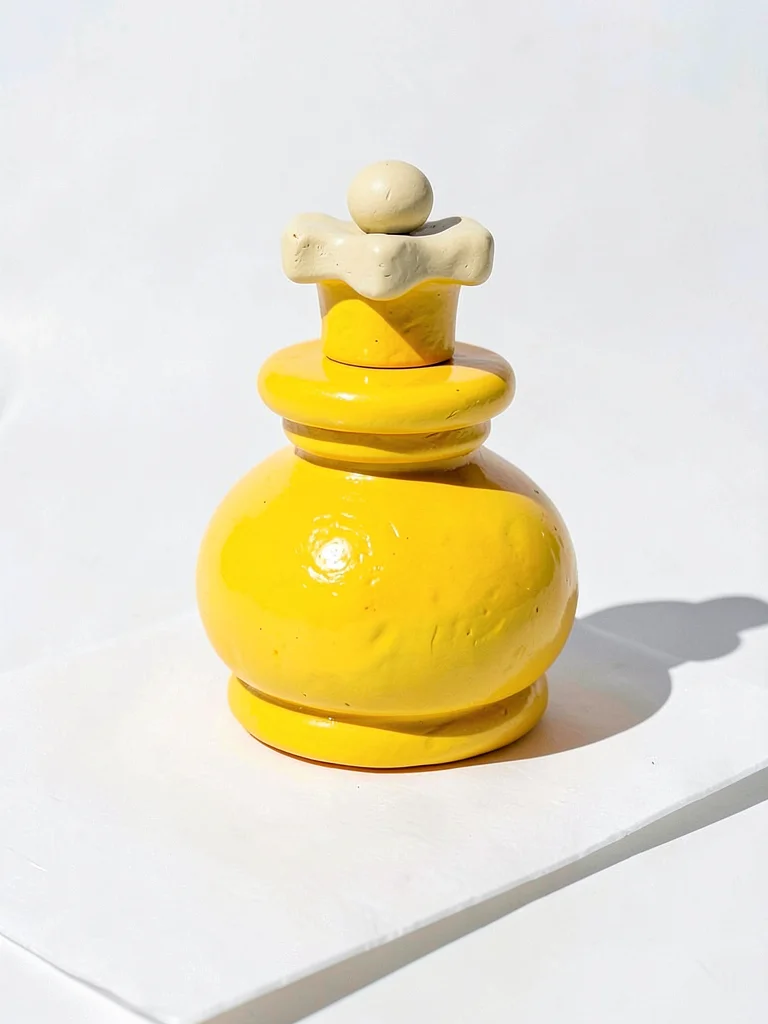 Compact chunky clay chess king in primary yellow with stubby cream-toned cross t