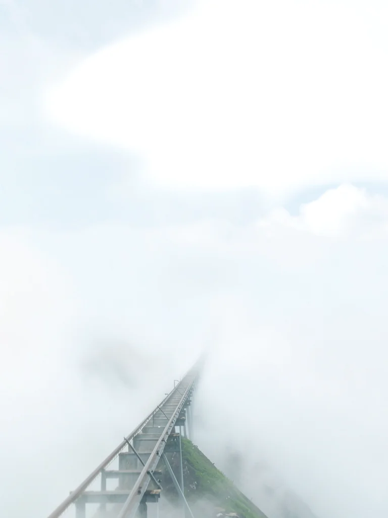 Steep funicular line climbing into cloud, lower tracks visible, upper terminal e