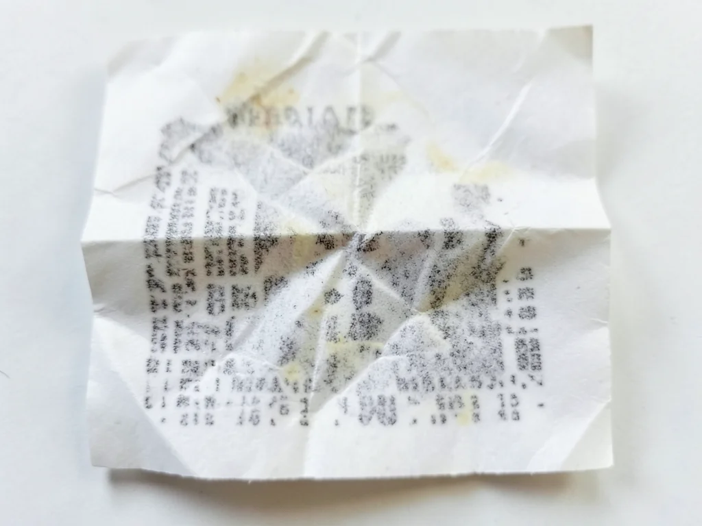 Receipt crumpled and partially smoothed, crinkle texture overlaid on fading prin