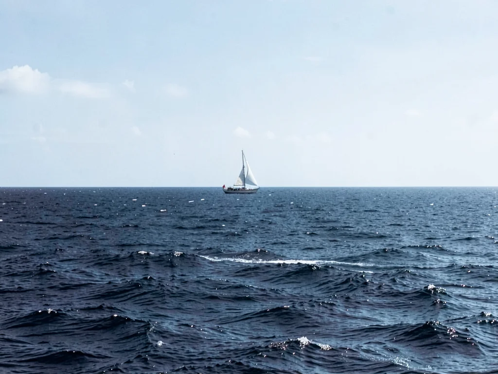 Ocean horizon where single sailboat sat still long enough to be captured